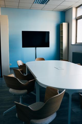 Comfortable chairs and oval table in modern conference room with TV on daytime